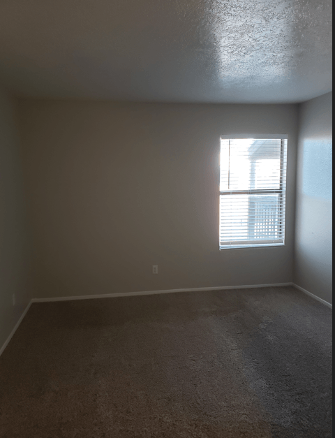 A room with a window and carpeted floor.